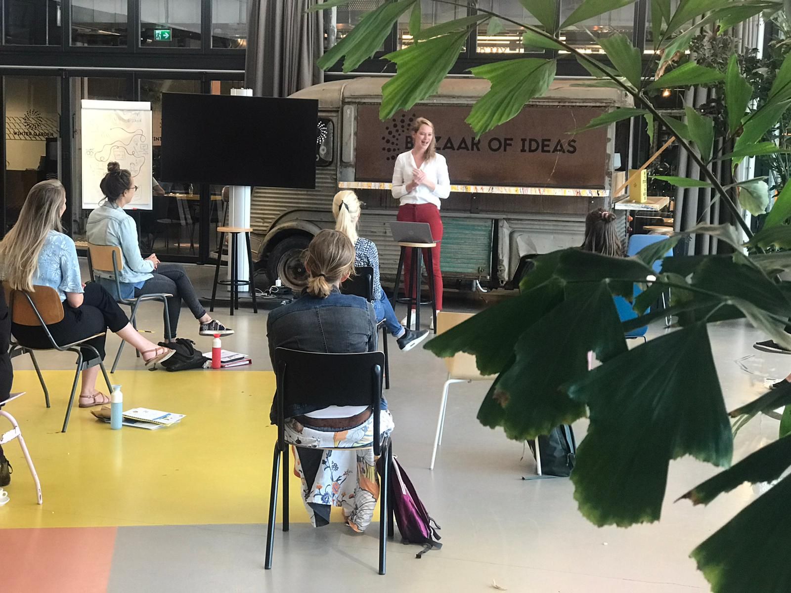 A group of participants engaged in a training session, seated around a table with a facilitator presenting